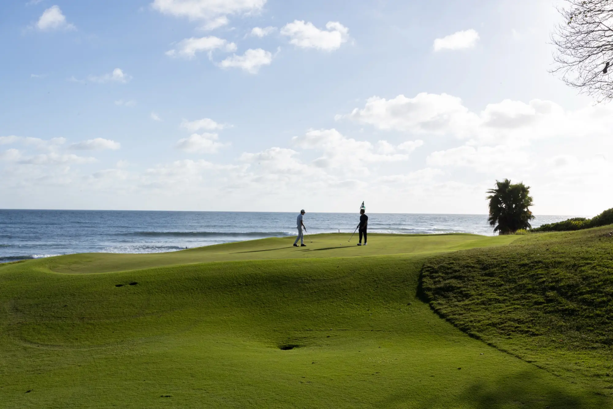 Two golfers on an oceanfront green at Punta Mita.